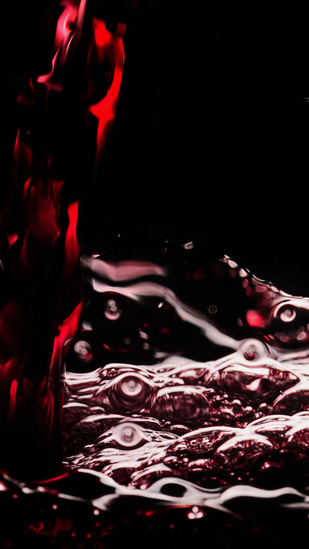 Close-up of red wine with visible bubbles against a dark background