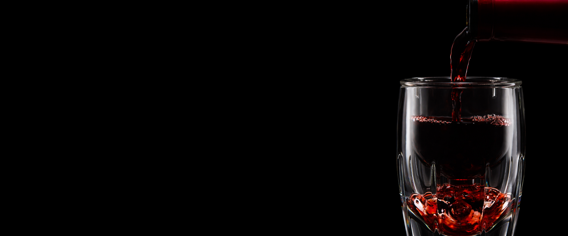 Red wine being poured through a wine aerator against a black background