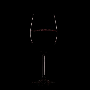 Wine glass with red wine against a black background
